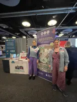 [Rosie and Erin stand next to a promotional banner for Make Your Mark that says "Help care for and celebrate Scotland's places and stories!".